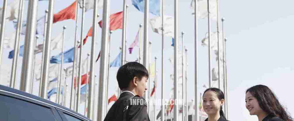 Three businesspeople meeting outdoors with flagpoles in background. Although she has not completed formal interpreter training, she brings substantial hands-on experience in consecutive interpreting and client communication.